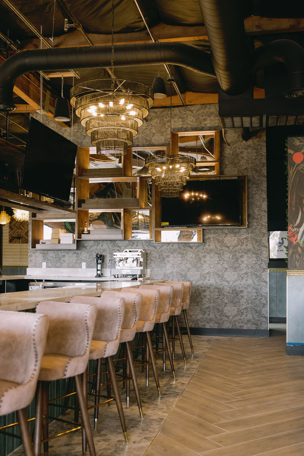 DodoBird restaurant bar with tiered brass chandeliers and tufted bar stools