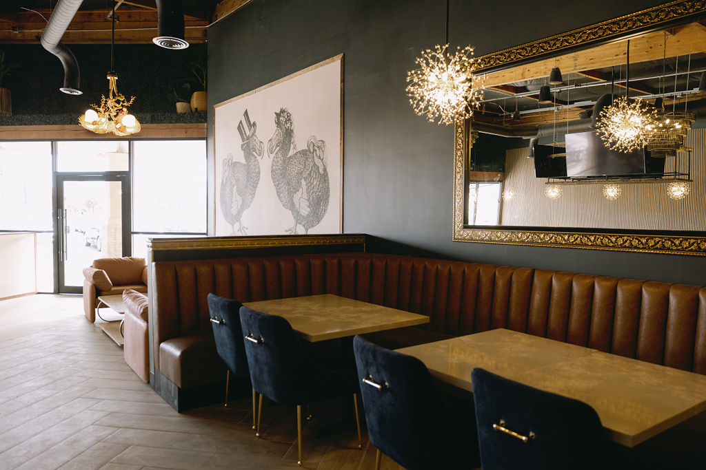 DodoBird dining room with leather banquette, dodo bird illustration, and gold-framed mirror